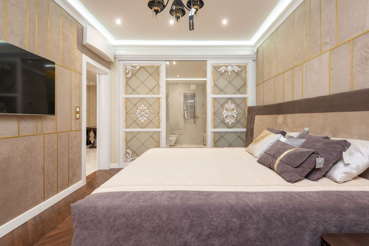 A bright, elegantly furnished bedroom with soft drapes and layered bedding